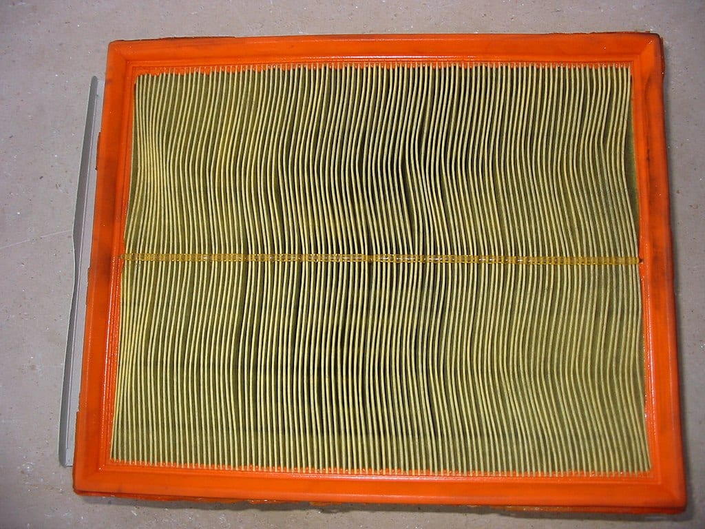 An orange and black air filter on a floor.